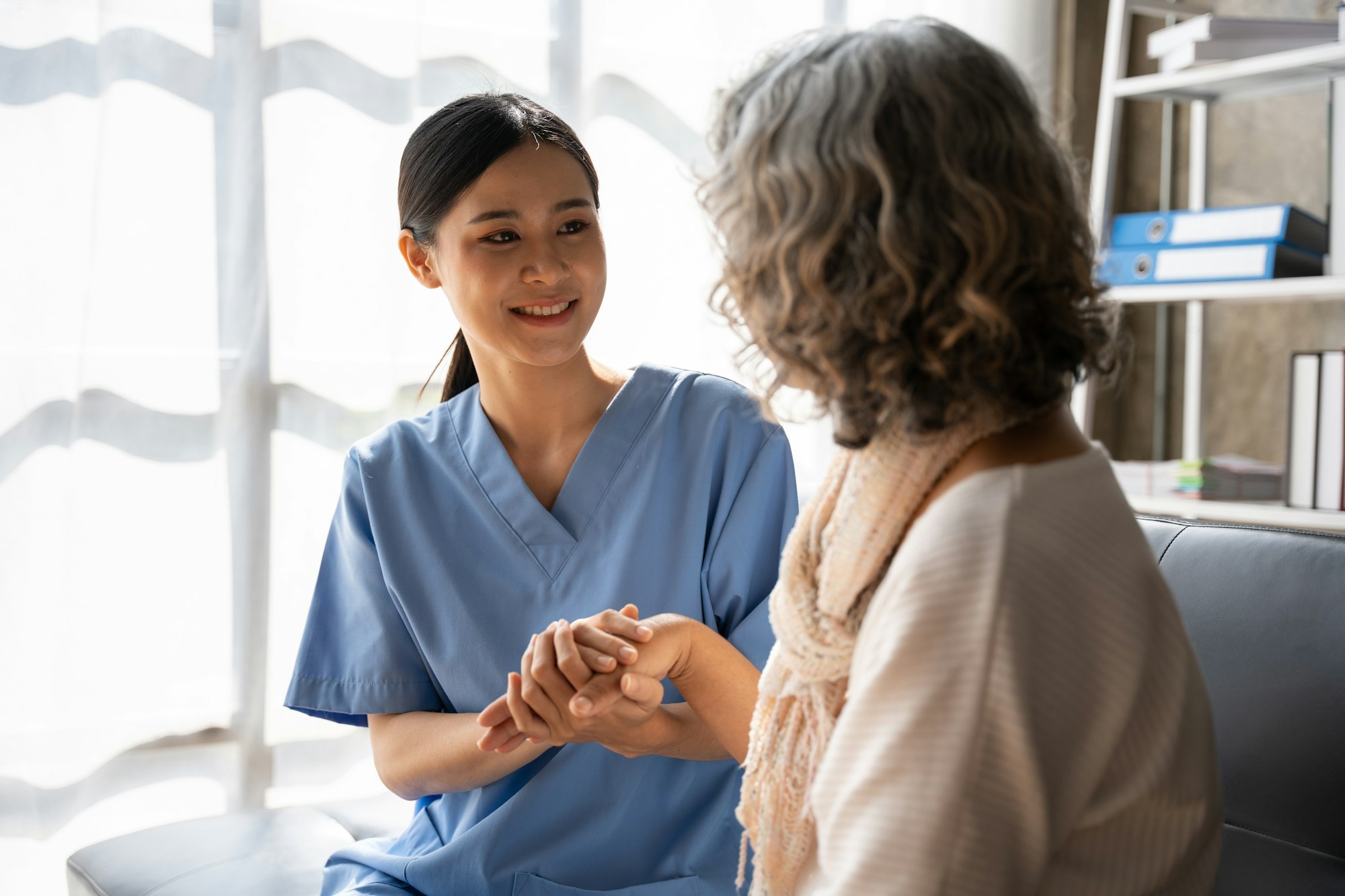 Asian young nurse supporting elderly patient disabled woman in hospital. Elderly patient care concep