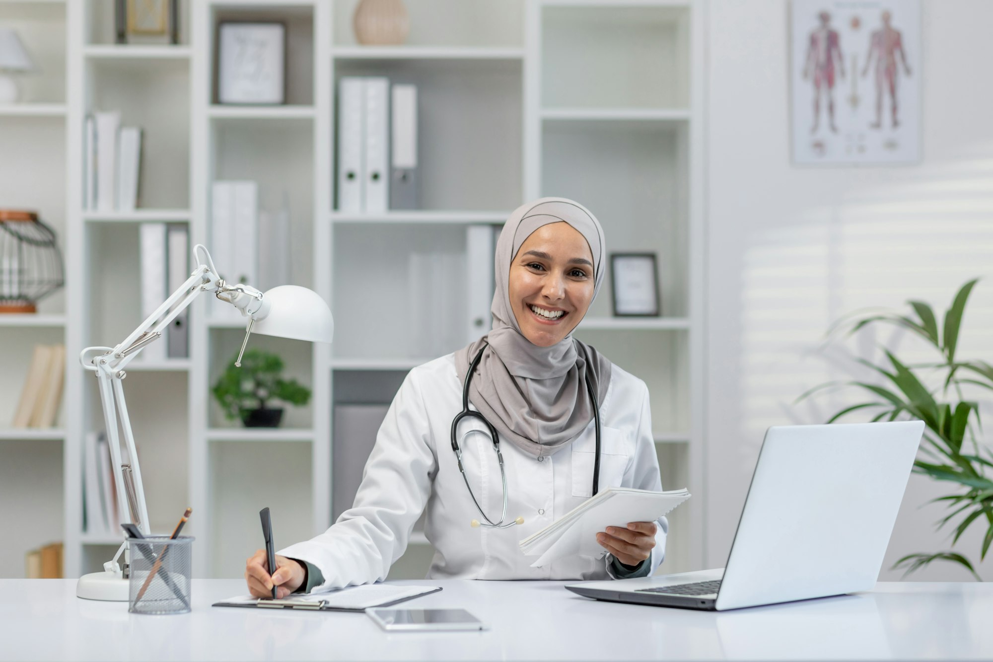 Friendly female doctor in hijab smiling at her desk